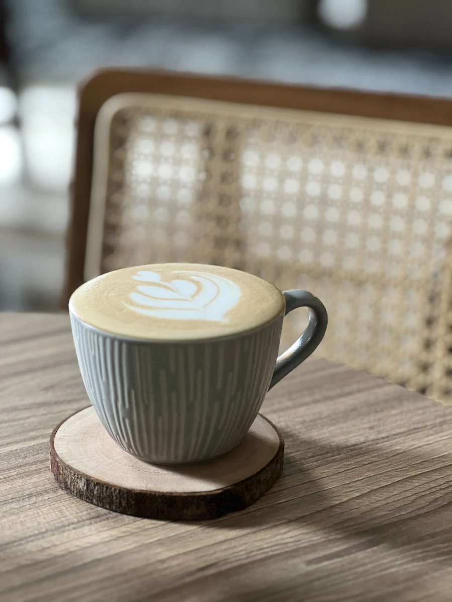 Xícara de café com leite decorada sobre mesa de madeira